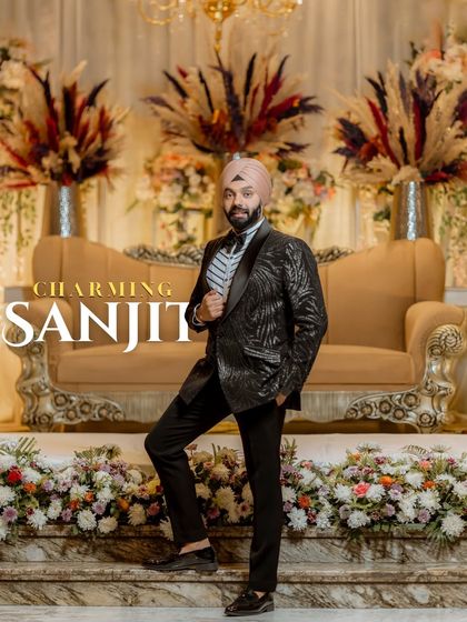 A dapper portrait of the groom, Sanjit. His confident pose against the elegant stage decor highlights his sharp style and the celebratory atmosphere.
