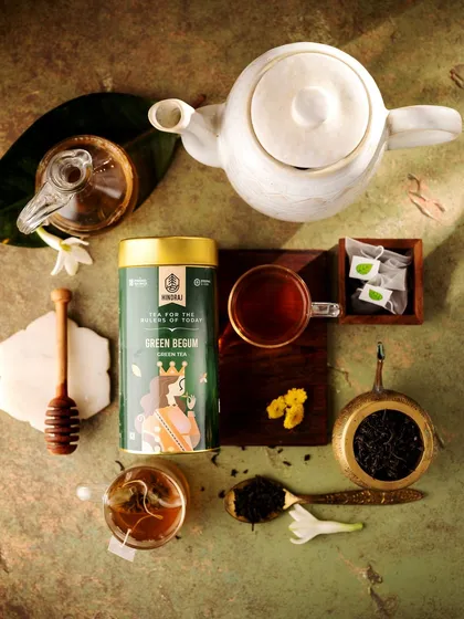 A beautiful flatlay of the Green Begum tea, deconstructed with loose leaves, tea bags, and a honey dipper. This top-down composition is both artistic and informative, showing the different ways to enjoy the tea.