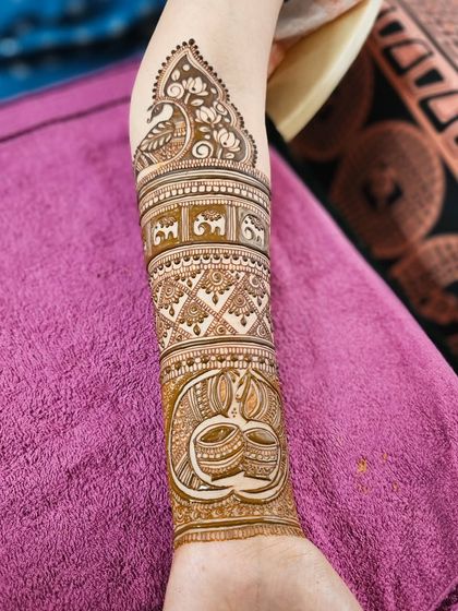 A close-up of the forearm, featuring a traditional kalash and a band of elephants.