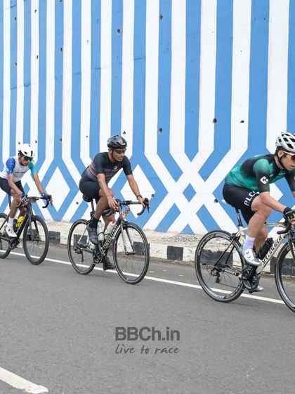 A group of amateur riders against a striking blue and white wall, adding an artistic touch to the race photo.