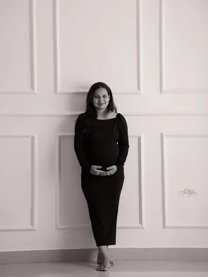 A simple yet elegant full-length portrait in monochrome. The clean lines of the wall paneling and the classic pose create a timeless feel.
