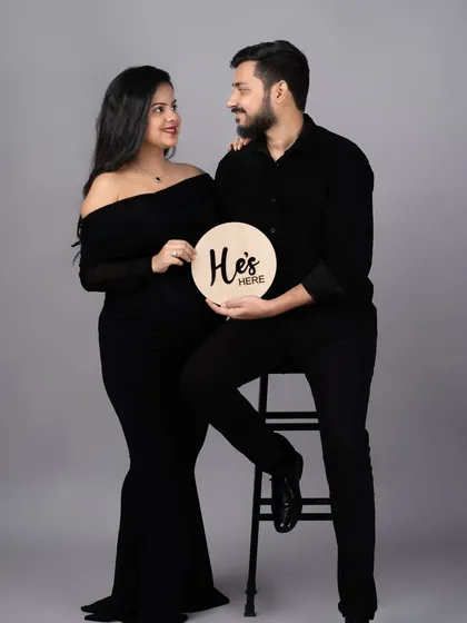 "He's here." A creative announcement photo taken after the baby's arrival, using a prop from the maternity session to tie the story together.