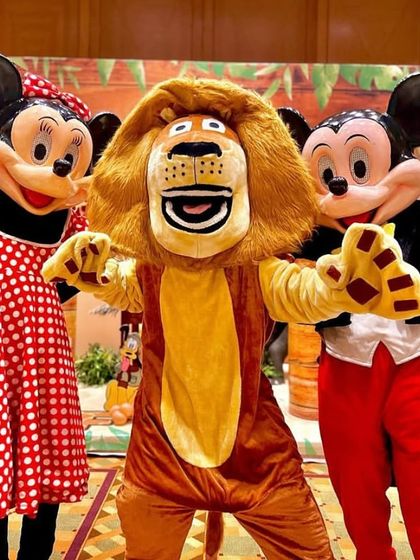 Mascots bring the party to life! Here, Mickey Mouse, Minnie Mouse, and Alex the Lion from Madagascar pose for a photo, ready to entertain the guests at a jungle safari birthday.