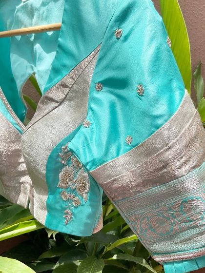 A side view of the turquoise patchwork blouse, showing the use of a silver Benarasi border on the sleeve and pleated cuff details.