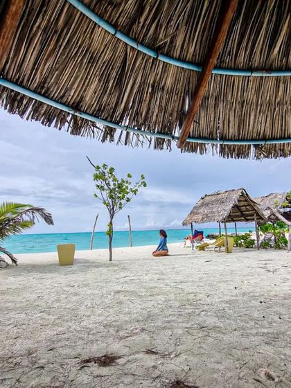 Post-dive relaxation is a key part of the experience. Here, a diver enjoys the serene beauty of a white sand beach in Gaafaru, the perfect way to unwind after a day of exploring the reefs.