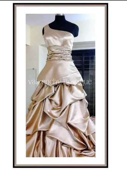 I crafted this elegant evening gown from shimmering champagne satin. The design features a contemporary one-shoulder neckline, a finely ruched bodice to ensure a perfect fit, and a dramatic tiered skirt with cascading drapes. This is the kind of custom formal wear I love to create for special occasions.