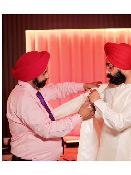 A touching moment between the groom and his father, who is helping him put on his wedding sherwani. This photo captures a special family bond and a traditional part of the getting-ready process.