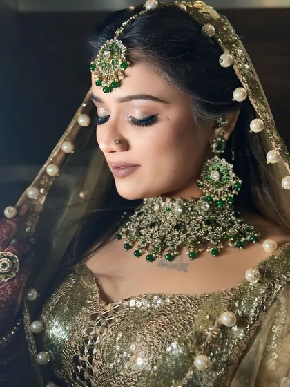 A close-up on the makeup and the stunning green jewellery set against the golden outfit.