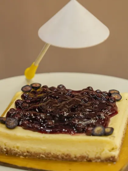 A slice of classic blueberry cheesecake, generously topped with a rich berry compote.