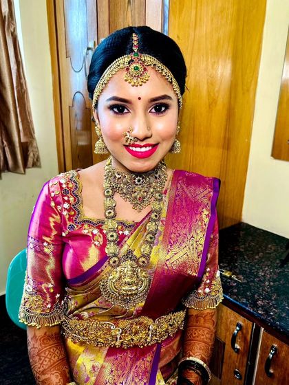 A classic bridal portrait. The model wears a full temple jewellery set, including a matha patti, choker, and haram.