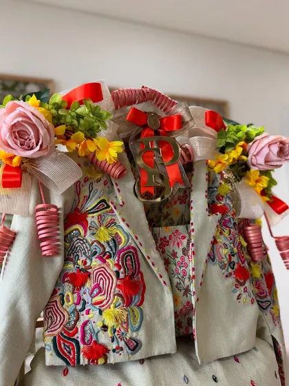 A close-up of the groom's vibrant outfit, adorned with colorful floral arrangements and playful details that match its festive energy.