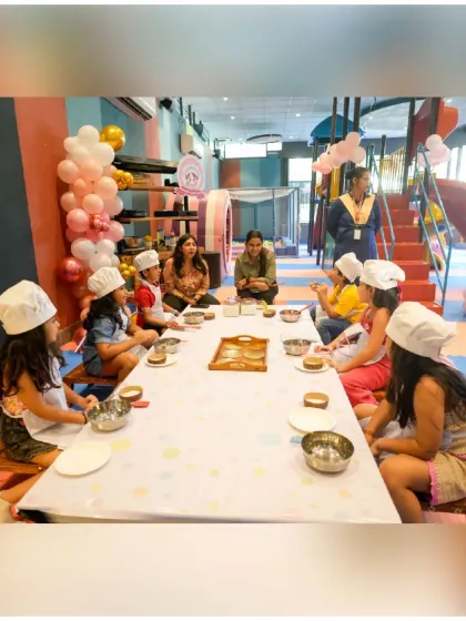 An overview of our baking workshop setup. Children are seated at a long table with individual stations, ready to learn and create with guidance from our staff.