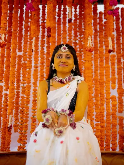 The bride glows against a classic Haldi backdrop. I created a dense wall of bright orange marigold garlands, a timeless and auspicious choice for the Harishina Shastra ceremony.