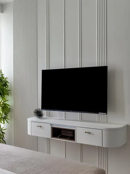 Another angle of the sleek, floating TV unit, highlighting its curved edges and the beautiful texture of the paneled wall behind it.