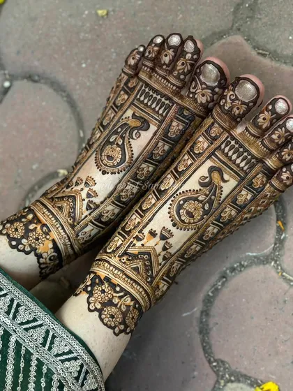 A top-down view of the intricate bridal foot mehendi, highlighting the detailed peacock and architectural motifs.