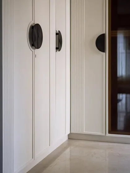 A closer look at the custom wardrobe doors, featuring vertical grooves and unique semi-circular handles. These details add a touch of bespoke craftsmanship to the space.