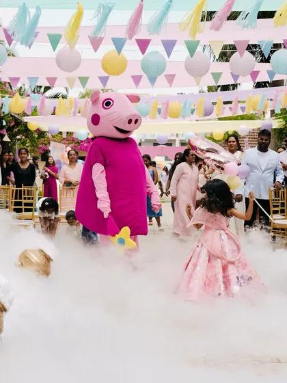 A moment of pure joy as the birthday girl meets Peppa Pig. This photo captures the magic of interactive entertainment, with a character mascot making a grand entrance through a cloud of fog, creating a storybook memory that will last a lifetime.