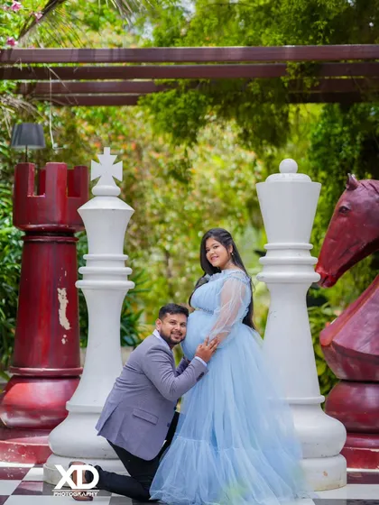 A classic pose with the father-to-be kneeling to kiss the belly, set against the fun backdrop of a giant chessboard.