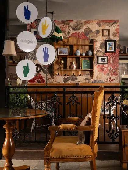 The eclectic mix of vintage furniture, a custom sign, and a floral wallpaper backdrop defines the unique character of Echoes. It's a space where different styles and eras come together to create a harmonious and inviting whole.