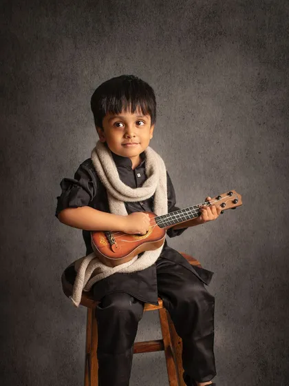 Another shot of our little musician, looking off-camera with a thoughtful expression. The dark background adds a touch of drama.