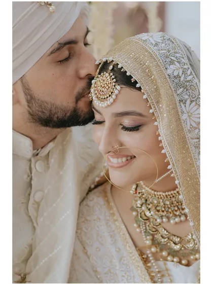 The gentle press of a kiss on the forehead is a universe of love. This tender moment from a Nikaah ceremony, captured in our signature clean and elegant style, speaks volumes about the couple's deep affection and bond.