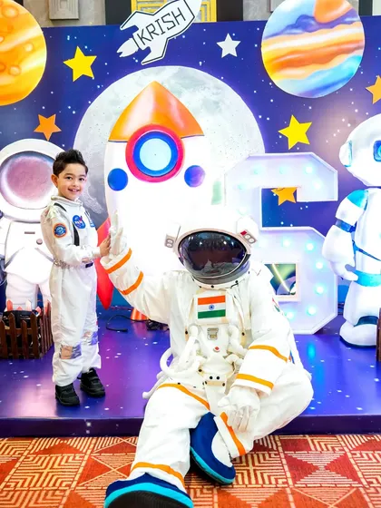 The birthday boy, dressed in a custom astronaut suit, poses with a life-sized astronaut mascot for an out-of-this-world photo.