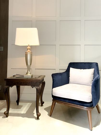 A single blue velvet armchair paired with a classic carved side table. This composition highlights how we balance ornate and simple forms within a single aesthetic.