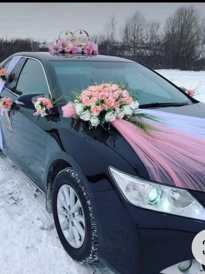 This black sedan is decorated with pastel pink roses and white fabric. This elegant and understated design is perfect for a modern or winter wedding.