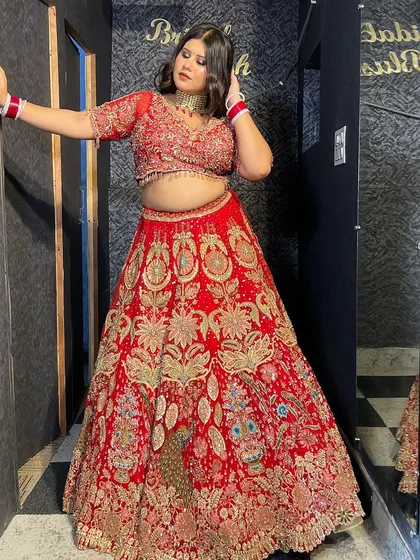 A full-length view of a stunning red bridal lehenga with peacock and floral embroidery. This is a statement piece for any bride.