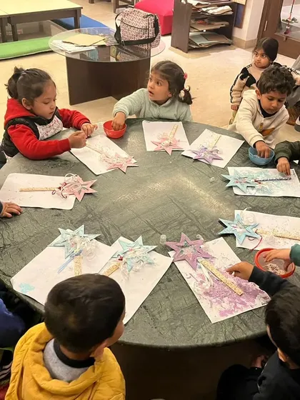 A group of toddlers decorating their wishing wands. This activity involves painting, gluing, and adding lots of sparkly details.