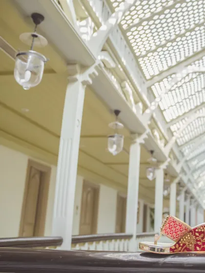 An artistic still-life of the groom's traditional wedding shoes (mojari) resting on a balcony railing. This shot highlights the small but significant details of the groom's attire.
