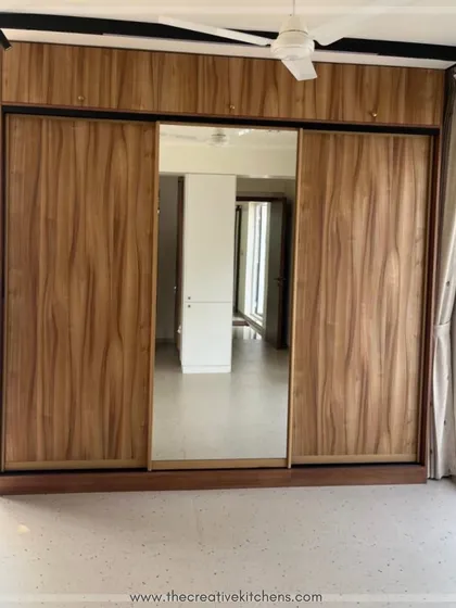 A classic and functional design, this sliding wardrobe features oak-finish shutters with inbuilt handles and a full-length central mirror. It's a seamless blend of style and convenience that elevates any bedroom.