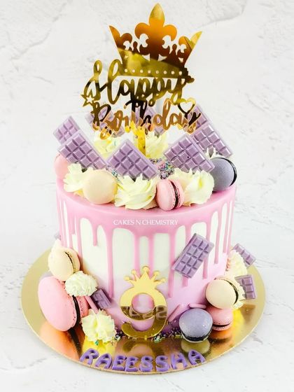A pretty pink drip cake perfect for a royal celebration. This Ferrero Rocher-flavoured cake is adorned with macarons, mini chocolate bars, and gold crown toppers for a fun and regal look.