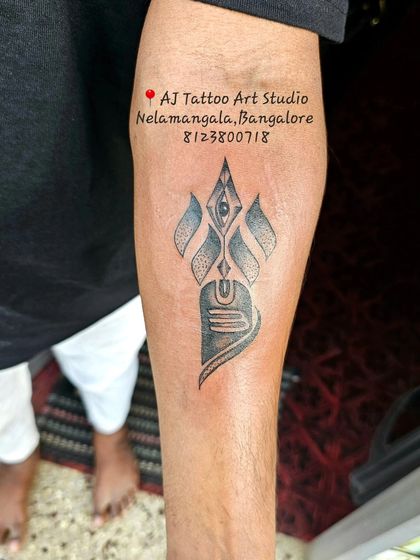 A modern, stylized Shiva Lingam tattoo with the third eye, inked on the forearm.