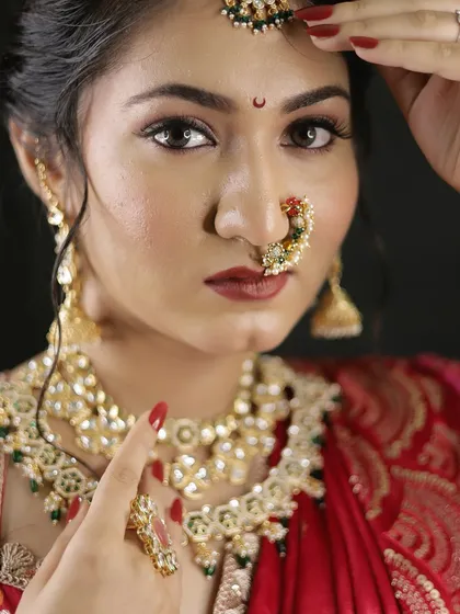 A powerful and intense close-up of a Maharashtrian bride. The focus is on the expressive eyes, the bold nath, and the rich red lip, creating a look of pure confidence.