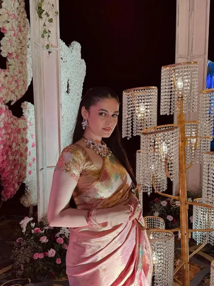 The client looks effortlessly chic with her hair pulled back into a simple ponytail, allowing her beautiful saree and jewelry to stand out.