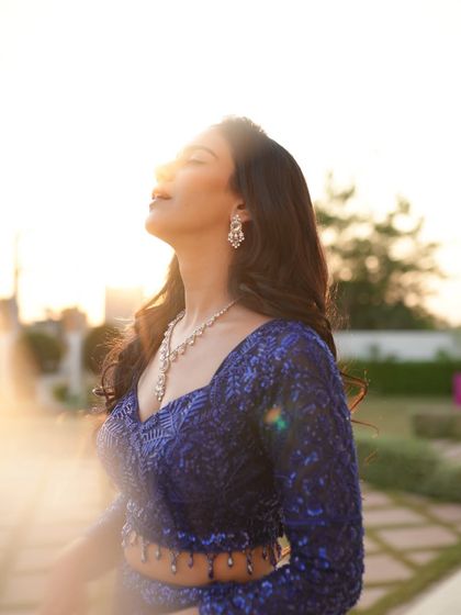 A beautiful sun-kissed close-up, where the golden hour light catches the sequins of the blue lehenga perfectly.