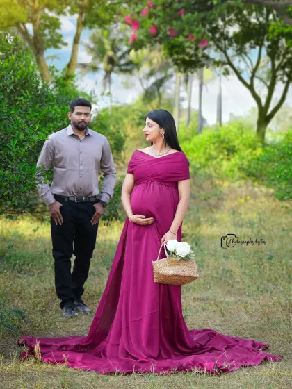 A beautiful solo portrait in a wine-colored gown. The mother-to-be is holding a basket of white flowers, adding a classic touch to the outdoor setting.
