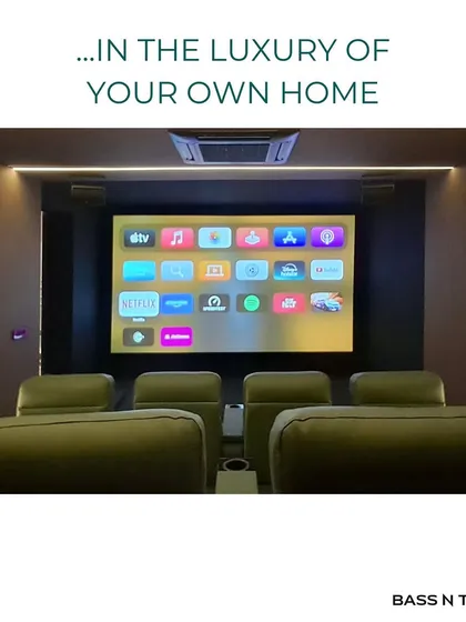 The front view of a 12-seater custom theatre, showing the large screen and perfectly integrated front speakers. The goal is to make the technology disappear, leaving only the cinematic experience.