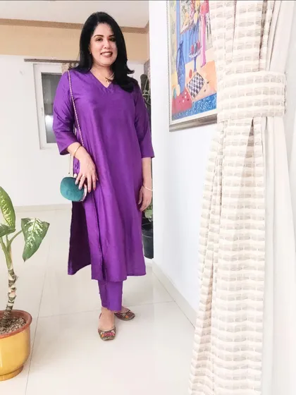 The complete look, showing how the green clutch bag adds a striking pop of contrast against the purple kurta set. This is a great way to experiment with colour blocking.
