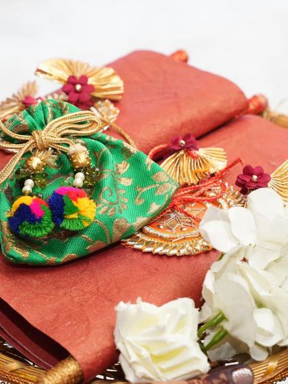 A set of wedding scrolls presented on a decorative tray with a small potli bag, showing how they can be part of a larger invitation hamper.