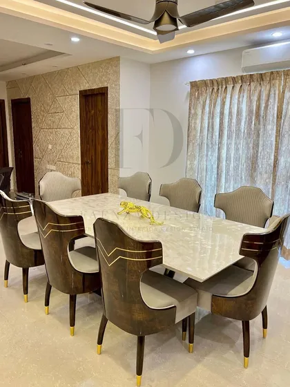 A full view of a grand dining set. The table is paired with chairs that feature a high-gloss wood finish and brass inlay, creating a cohesive and luxurious environment for formal dining.