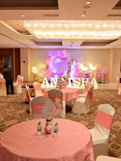 A wide view of the banquet hall for Anaisha's birthday, showing the main stage decor and the coordinated pink table settings for guests.