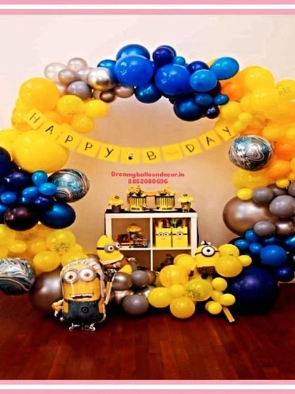 A fun-filled Minions birthday party setup. This decoration features a balloon arch in the signature blue and yellow colors, along with Minion character balloons and a themed dessert table display.