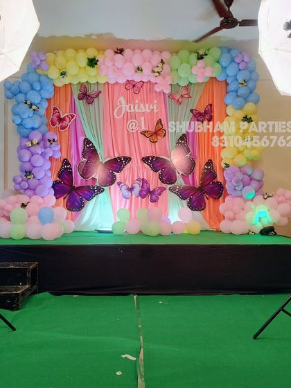 A beautiful butterfly garden theme for a first birthday, with a pastel balloon and fabric backdrop.