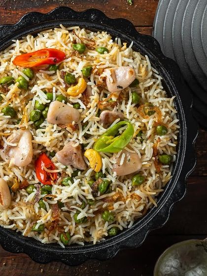A flavorful chicken pulao with peas and cashews, presented in a traditional handi for Punjab Grill.