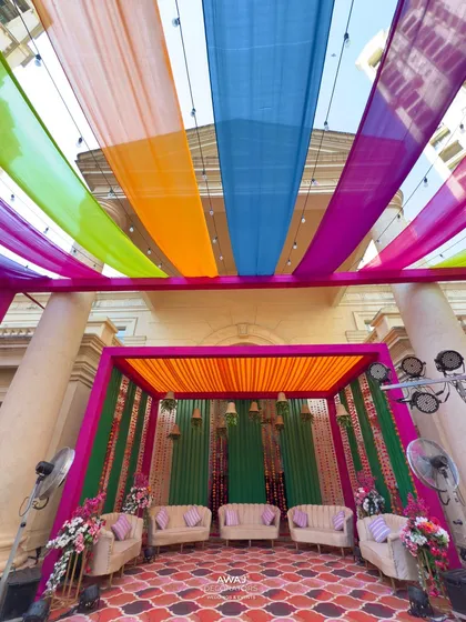 The full view of the vibrant Mehendi stage, set under a canopy of multi-colored drapes, ready for a day of fun and festivities.