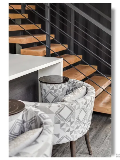 A close-up on the details where a floating staircase meets patterned dining chairs. This shot highlights the sophisticated interior design choices that elevate the container home's aesthetic.