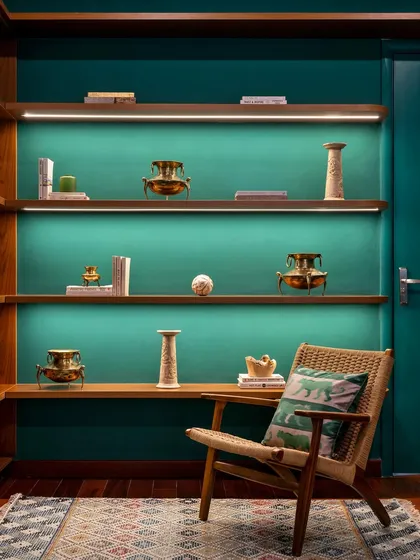 The home office in 'Vasudhalayah' features this stunning curio unit. Washed in emerald green, the floating shelves display the family's cherished heirlooms, turning a functional space into a personal gallery.