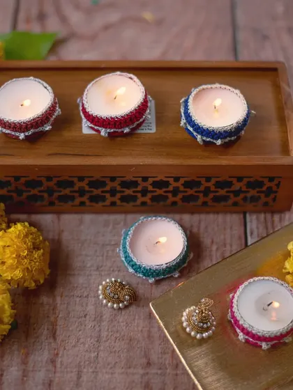 Our small crochet 'diya jackets' in red, blue, and green, displayed on a wooden tray. These are perfect for adding a touch of color to every corner of your home during festivals.